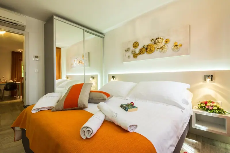 Une chambre lumineuse avec un grand lit recouvert d'une courtepointe orange et de coussins.