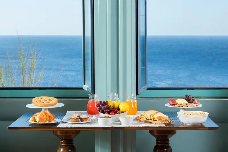 Une table de petit-déjeuner est dressée devant une grande fenêtre donnant sur la mer.