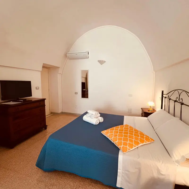 Une chambre lumineuse avec un lit recouvert d'une courtepointe bleue et orange.