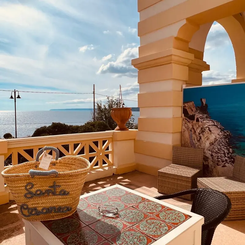 Terrasse carrelée avec mobilier en osier et vue sur la mer.