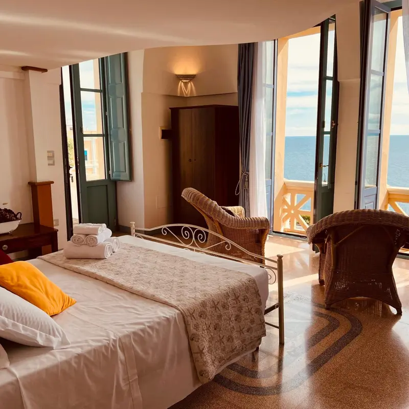 Une chambre lumineuse avec un lit fait et une vue sur la mer.