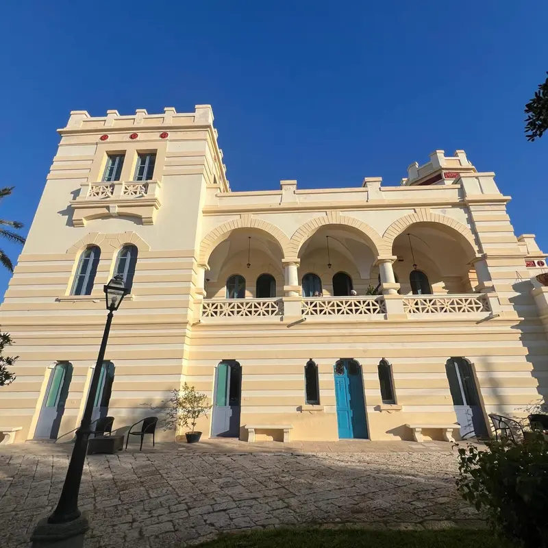 Bâtiment beige à plusieurs niveaux avec des arcades et des balcons.