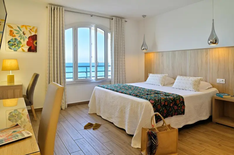 Une chambre lumineuse avec un lit double et une vue sur la mer.