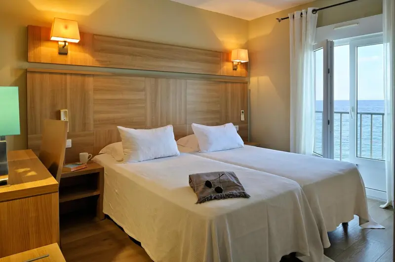 Une chambre lumineuse avec un grand lit et un accès à un balcon.