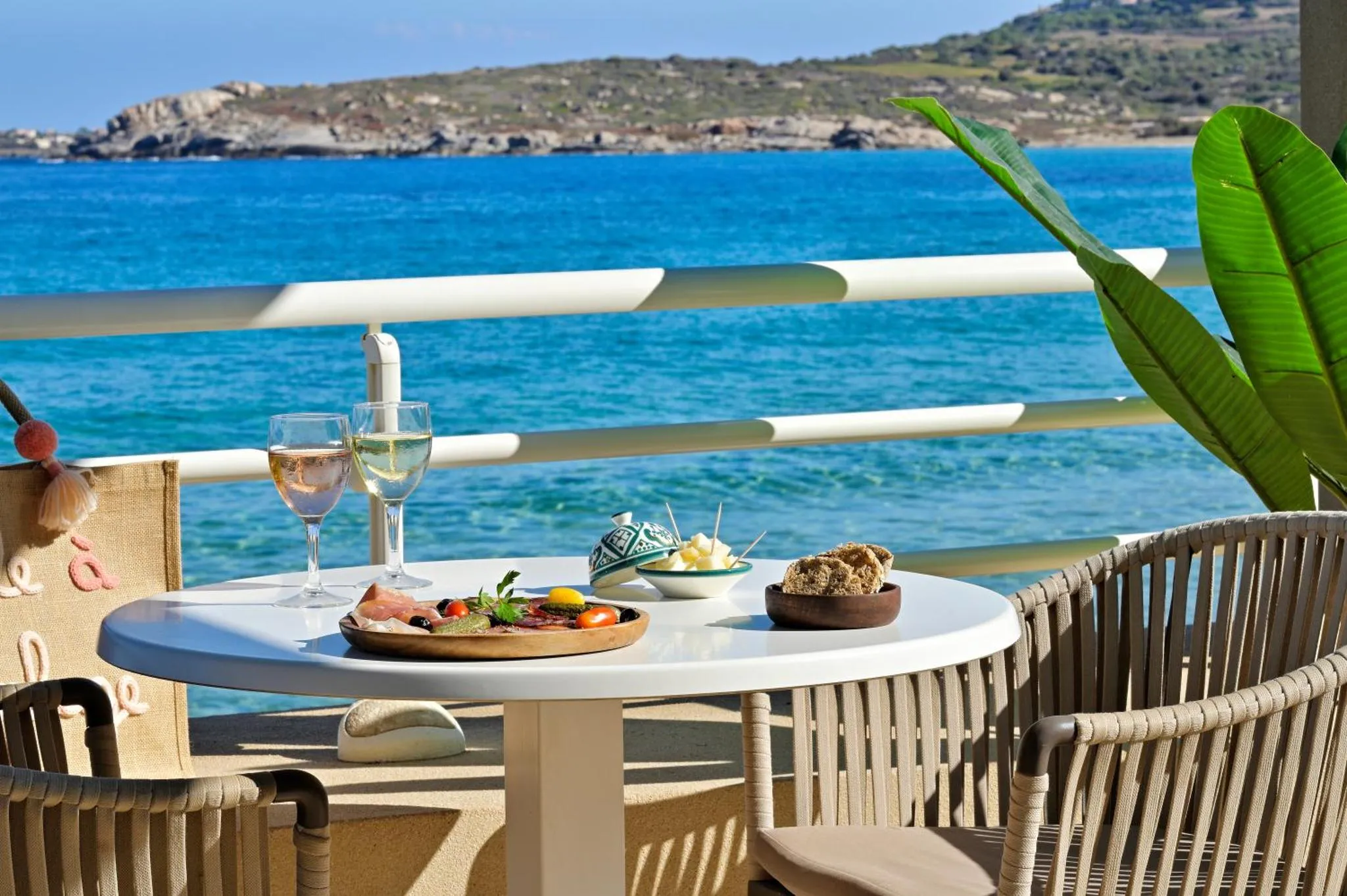 Une table est dressée avec des plats et des boissons sur une terrasse en bord de mer.