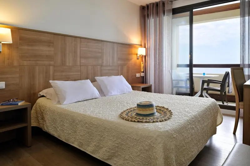 Une chambre lumineuse avec un grand lit et un accès à une terrasse.