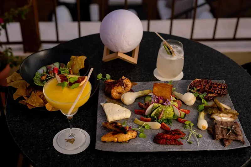Une table ronde présente une sélection de plats et de boissons colorées.