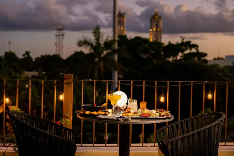 Une table ronde est dressée sur une terrasse avec des plats et des boissons.