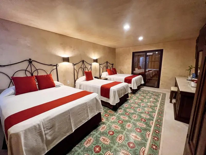 Deux lits avec couvre-lits rouges dans une chambre décorée de murs texturés.