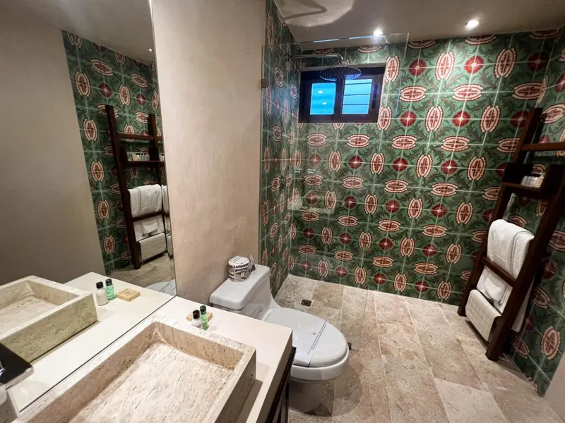Une salle de bain lumineuse avec des murs décorés et un grand miroir.