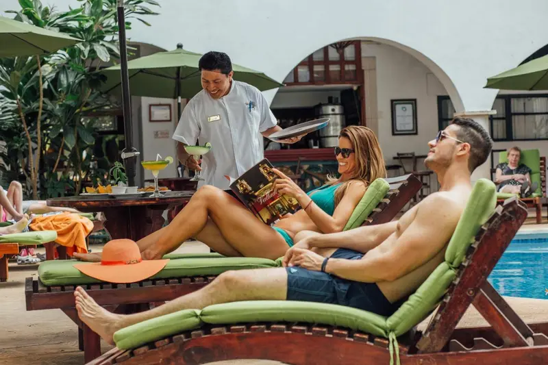 Des clients se détendent sur des transats au bord d'une piscine ensoleillée.