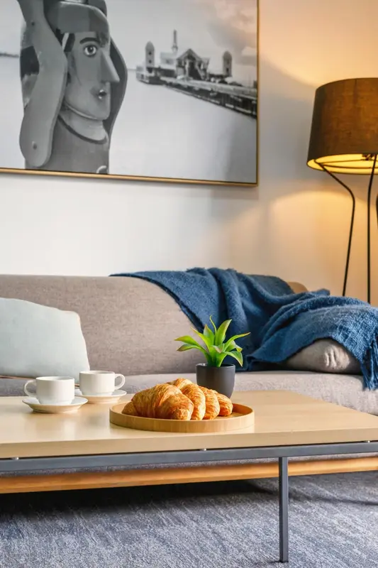 Une table basse avec des viennoiseries et une tasse de café devant un canapé.