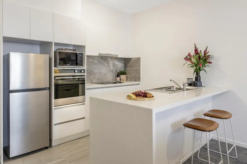 Cuisine moderne avec un îlot central et des tabourets.