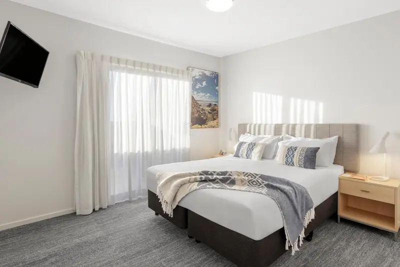 Une chambre lumineuse avec un grand lit et des rideaux blancs.