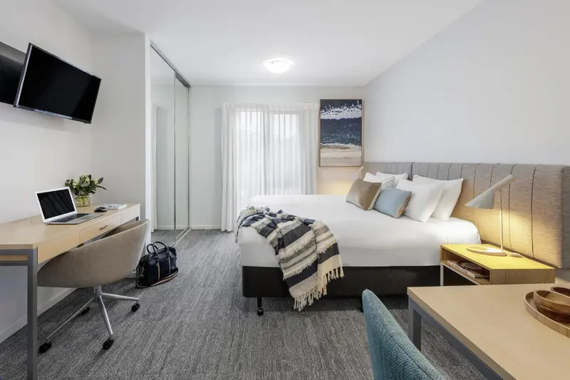 Une chambre lumineuse avec un grand lit et un espace bureau.