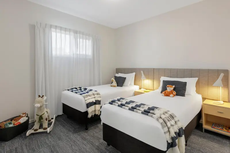 Une chambre lumineuse avec deux lits simples et une décoration sobre.