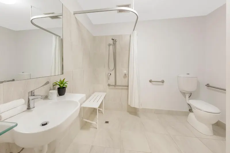 Une salle de bain claire avec douche et lavabo.