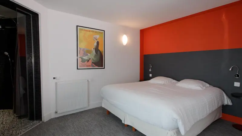 Une chambre lumineuse avec un lit blanc et un mur orange décoré d'une affiche.