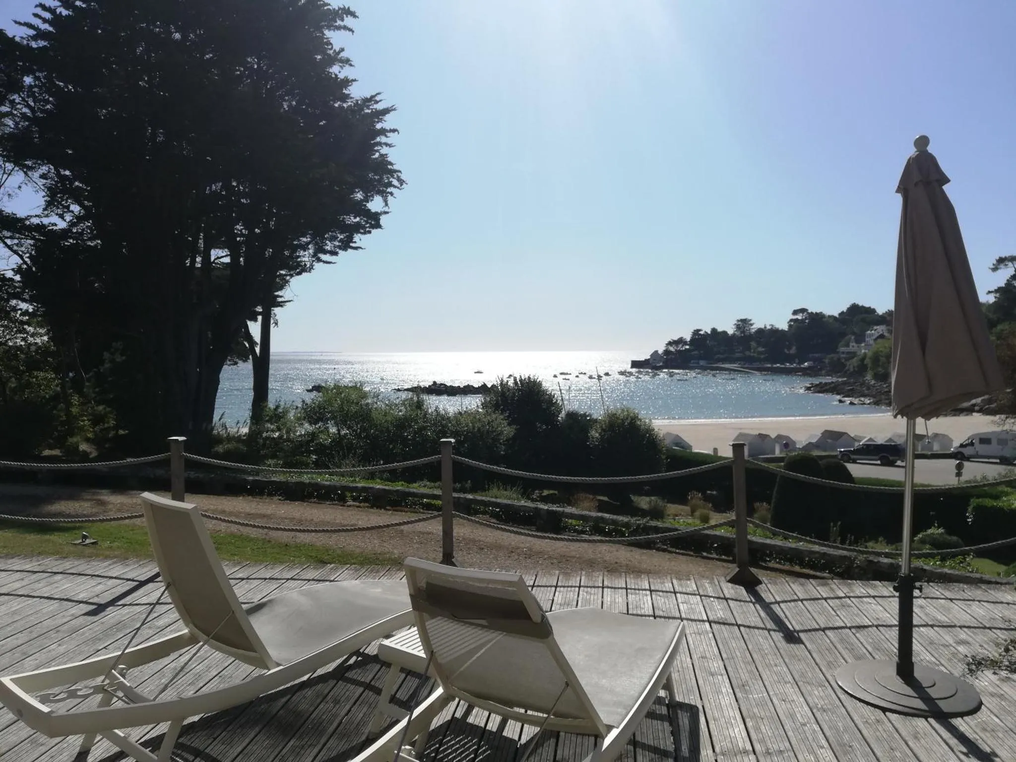 Terrasse en bois avec transats face à la mer.