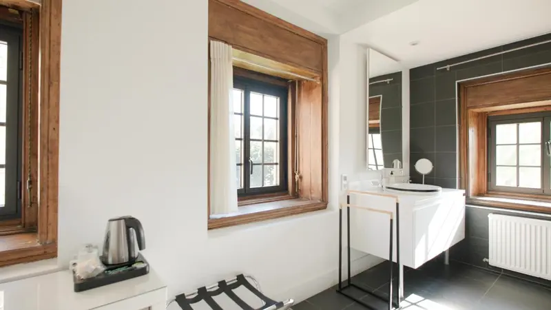 Une salle de bain lumineuse avec un lavabo moderne et des fenêtres.