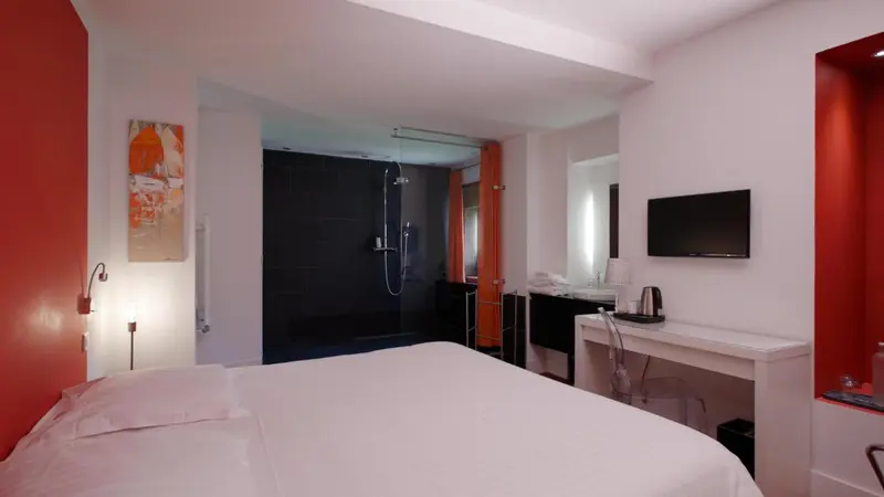 Chambre lumineuse avec un grand lit et une douche à l'italienne.