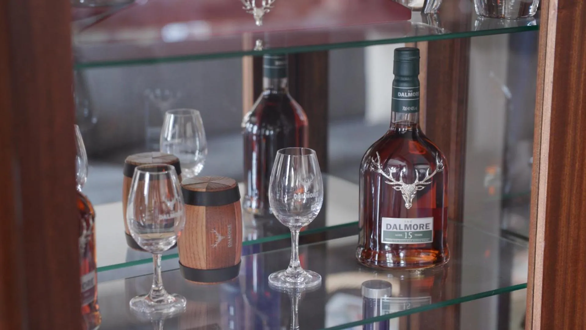 Une étagère en bois présente des bouteilles d'alcool et des verres.