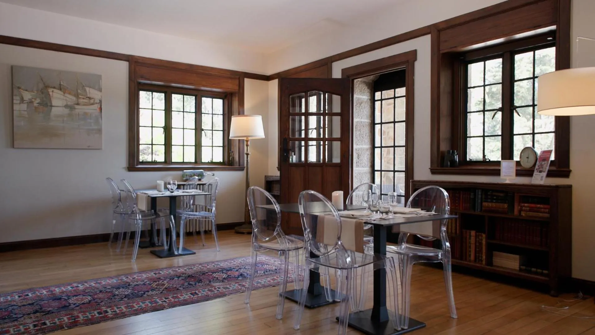 Une salle à manger lumineuse avec des tables dressées et des chaises transparentes.