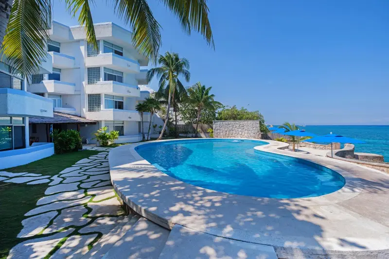 Une piscine bordée d'une terrasse ensoleillée avec une vue sur la mer.