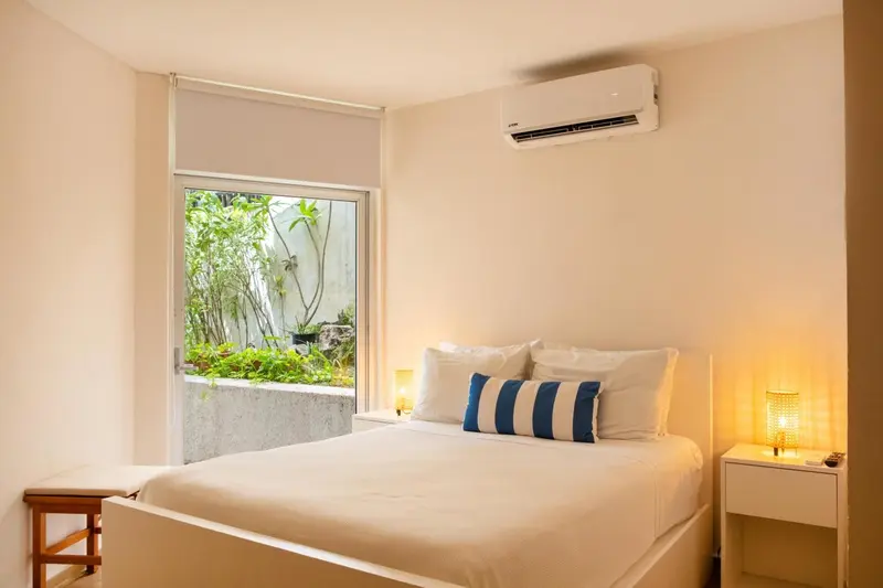 Une chambre lumineuse avec un lit double et une vue sur la végétation.