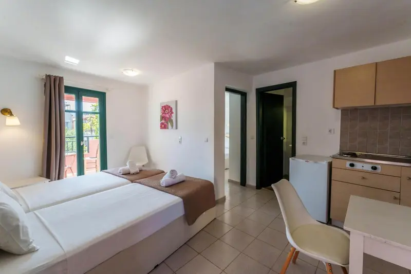 Une chambre lumineuse avec un coin cuisine et un lit double.