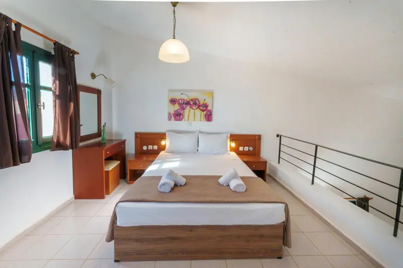 Une chambre lumineuse avec un lit double et un décor mural coloré.