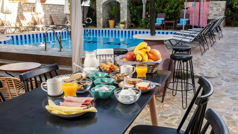 Une table de petit-déjeuner est mise en scène devant une piscine ensoleillée.