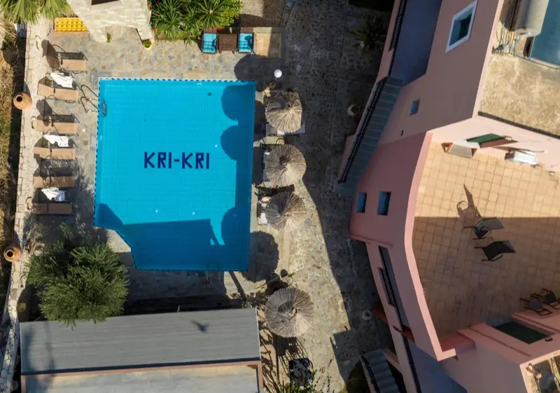 Vue aérienne d'une piscine rectangulaire et de bâtiments pastel.