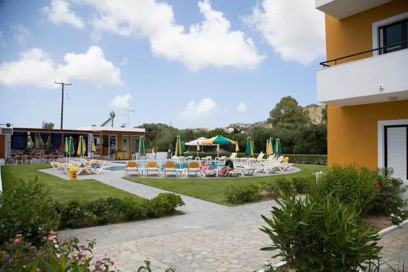 Transats colorés disposés autour d'une piscine dans un jardin verdoyant.