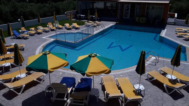 Transats et parasols disposés autour d'une piscine ensoleillée.