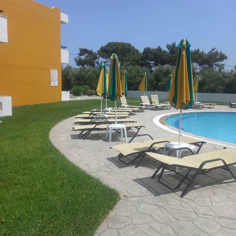 Transats et parasols colorés disposés autour d'une piscine ensoleillée.