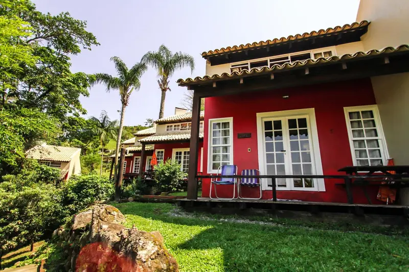 Bâtiment rouge à deux étages avec des fenêtres et une terrasse en bois.