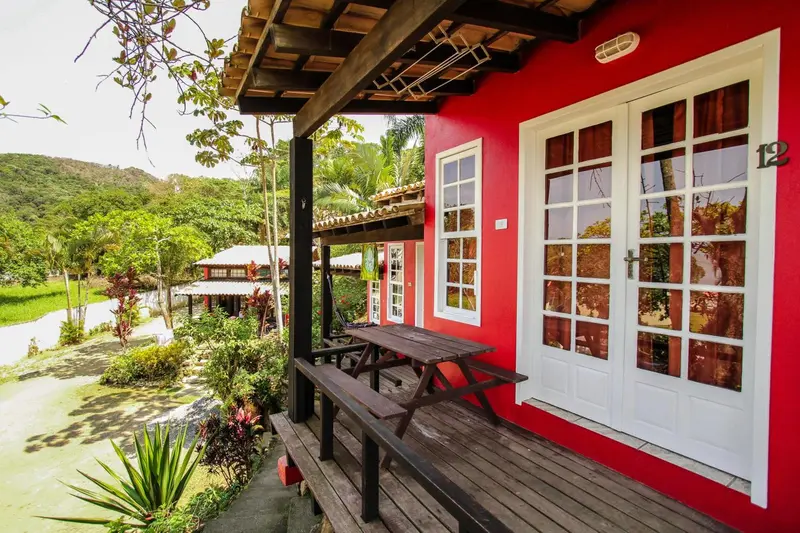 Façade rouge d'un bâtiment avec une terrasse en bois et une table.