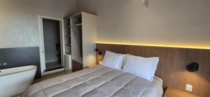 Une chambre lumineuse avec un grand lit et une baignoire.