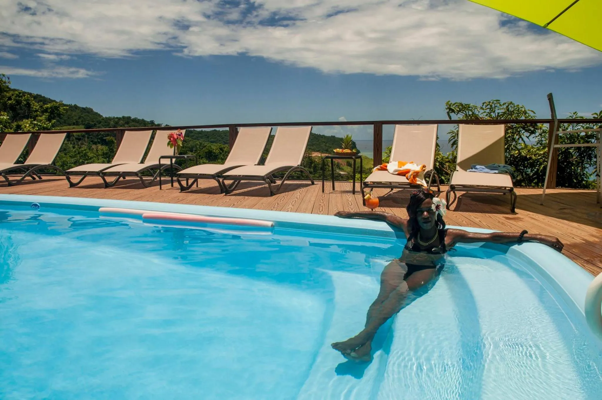 Une femme se détend dans une piscine au bord d'une terrasse ensoleillée.