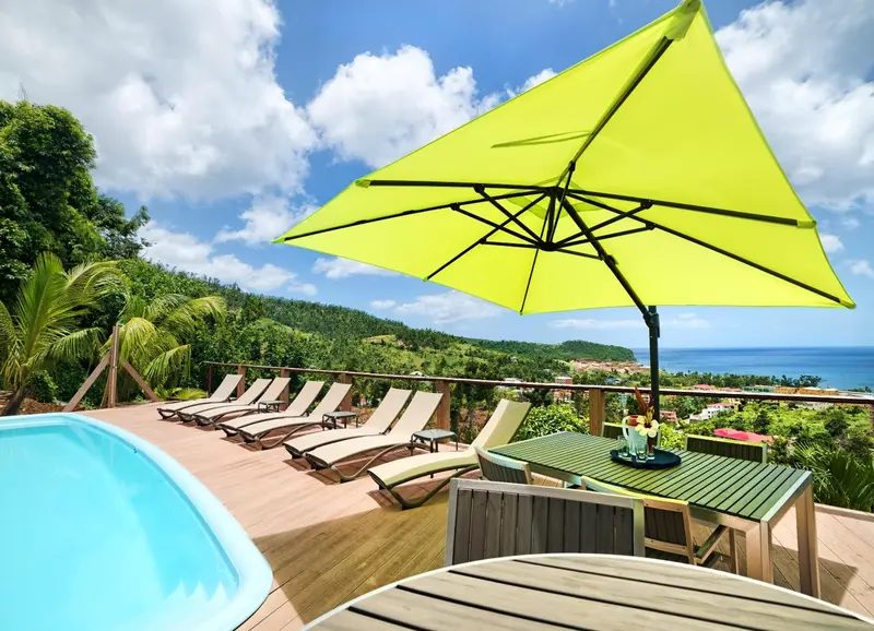 Terrasse avec transats et table basse offrant une vue sur la mer et les collines.