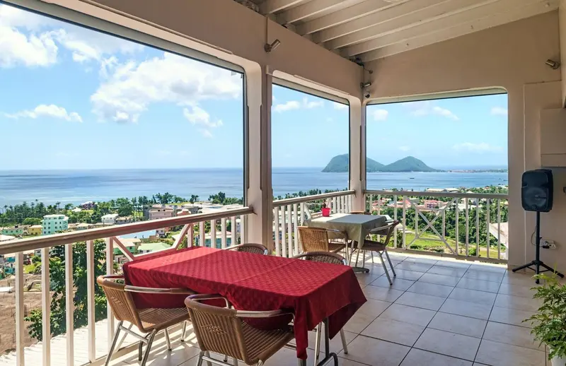 Terrasse ombragée donnant sur une vue panoramique de la mer et de la végétation.