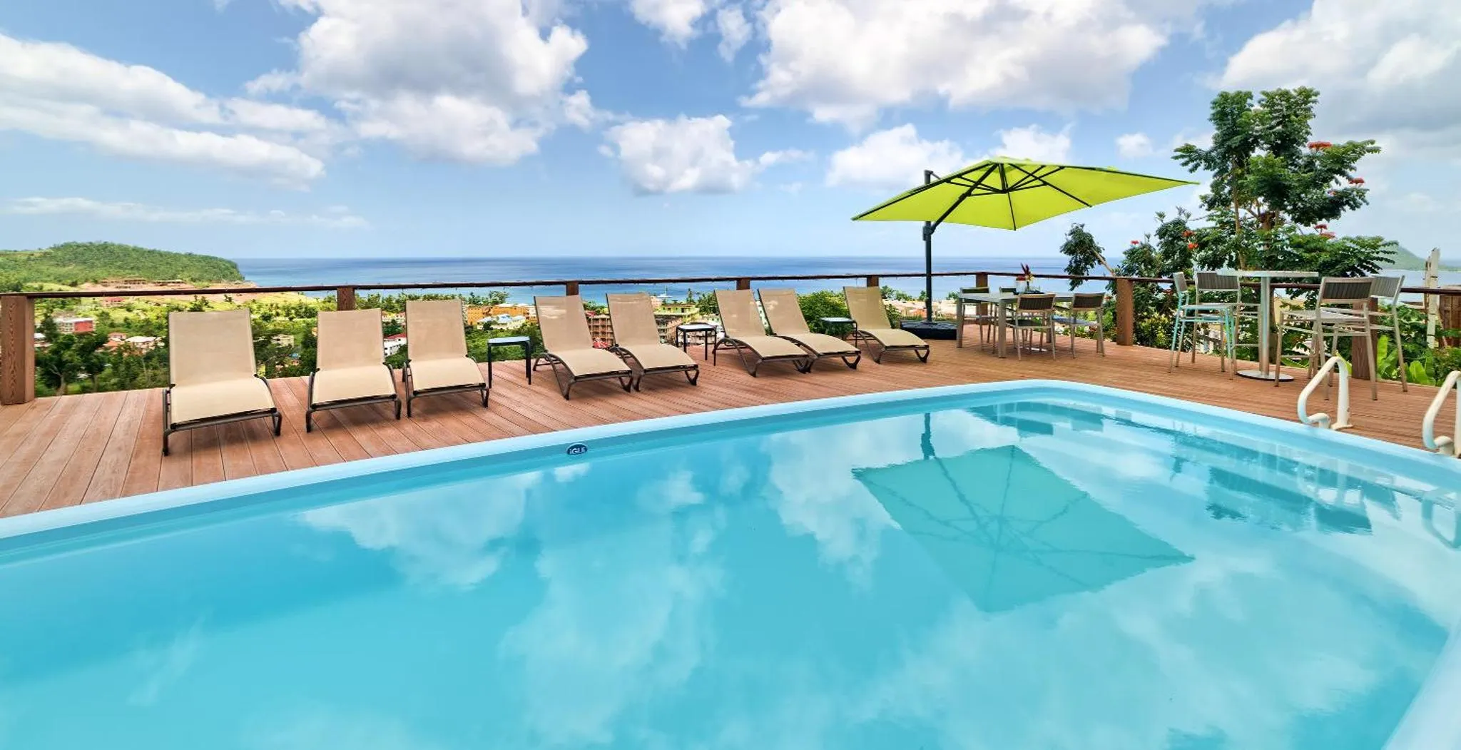 Transats alignés au bord d'une piscine turquoise avec vue sur la mer.