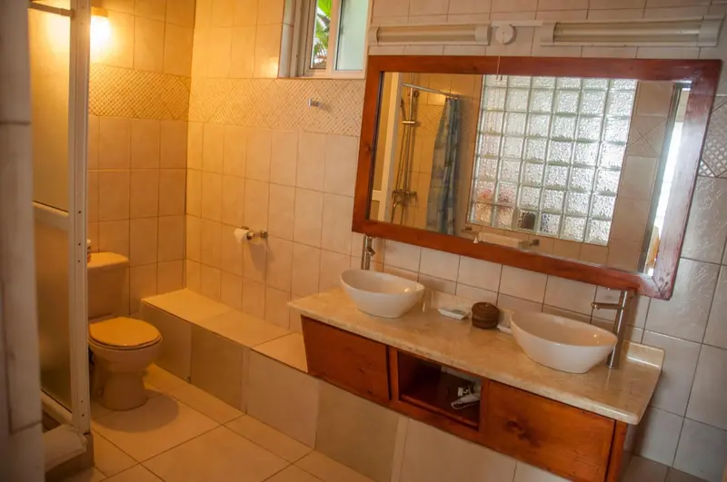 Une salle de bain lumineuse avec deux vasques et une douche.