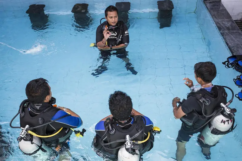 Des personnes équipées se tiennent dans une piscine turquoise.