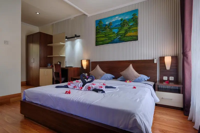 Une chambre lumineuse avec un grand lit décoré de fleurs et de serviettes en forme de cygnes.