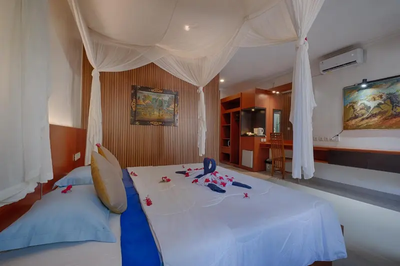 Une chambre avec un grand lit recouvert de moustiquaire et décoré de fleurs.