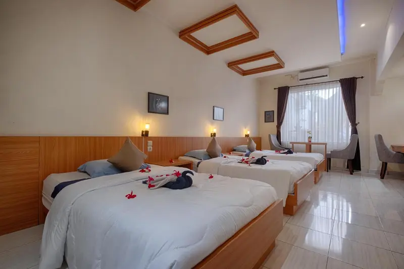 Chambre lumineuse avec deux lits simples décorés de fleurs et d'un cygne en serviette.