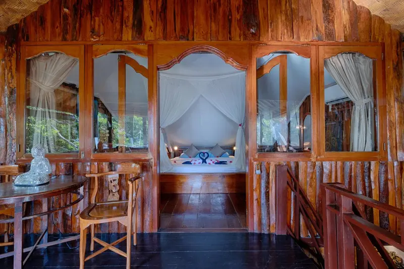 Intérieur chaleureux d'une chambre avec un lit à baldaquin et une table en bois.