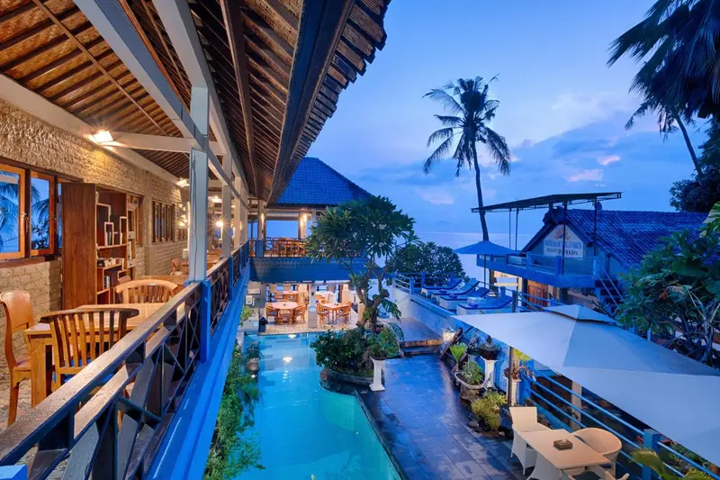 Terrasse avec vue sur une piscine et la mer au loin.